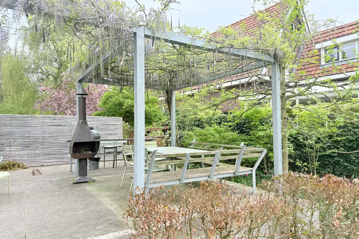 Stalen pergola, acht jaar oud, begroeid met groen in een tuin